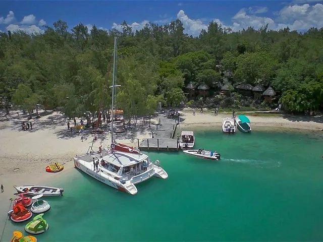 Vue aérienne de bateaux amarrés près d'une plage de sable avec une végétation luxuriante.