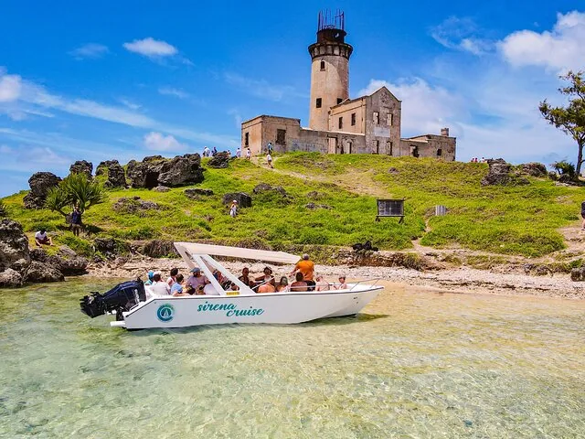Touristes sur une vedette rapide arrivant à une petite île avec un vieux phare.