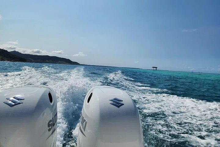 Vista desde la parte trasera de una lancha rápida en movimiento, mostrando la estela y las islas a lo lejos.