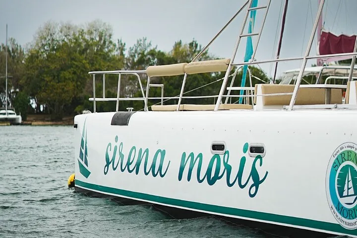 Nahaufnahme der Seite eines weißen Katamarans mit der Aufschrift 'sirena moris'.